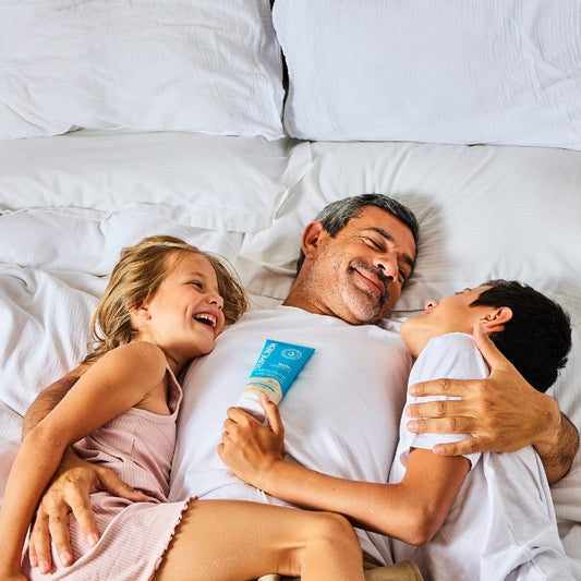 Un padre y sus dos hijos se ríen en una cama